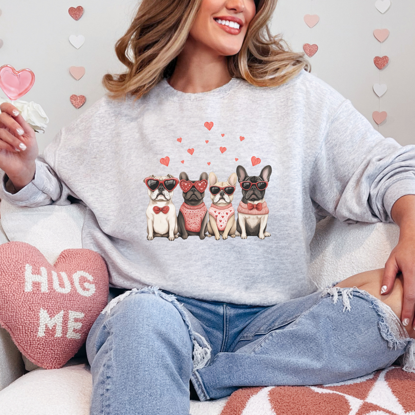 Cozy ash-gray Valentine's Day sweatshirt featuring a charming lineup of French Bulldogs adorned with heart-themed accessories, including sunglasses, bows, and scarves. The design is surrounded by scattered pink hearts, making it the perfect outfit for dog lovers to spread love and warmth.