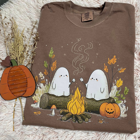 Folded brown sweatshirt with ghost design and autumn elements on a textured surface.