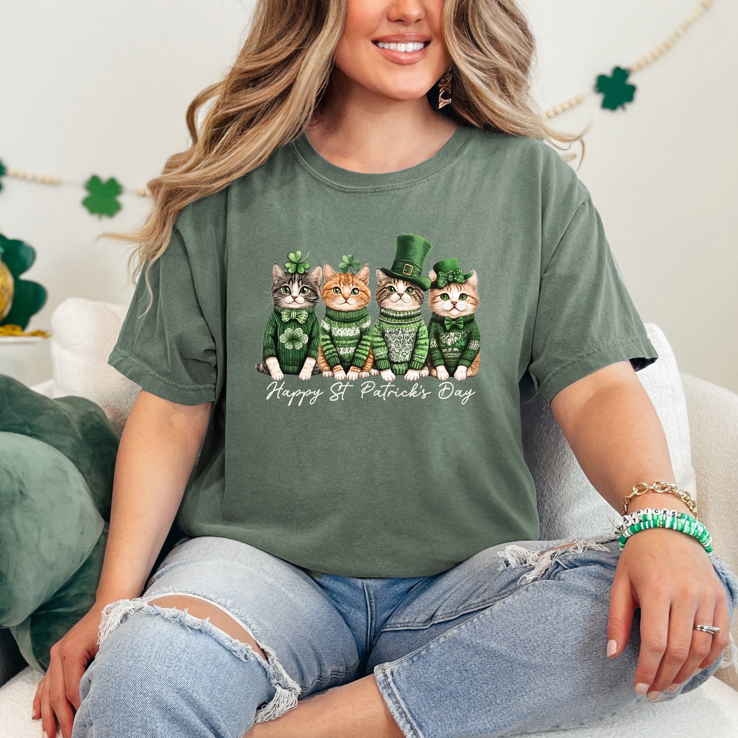 Moss green t-shirt featuring adorable illustrated cats dressed in festive St. Patrick's Day attire, including sweaters and a leprechaun hat. The text reads 'Happy St. Patrick's Day' in elegant white script. A playful and cozy option for celebrating the holiday.