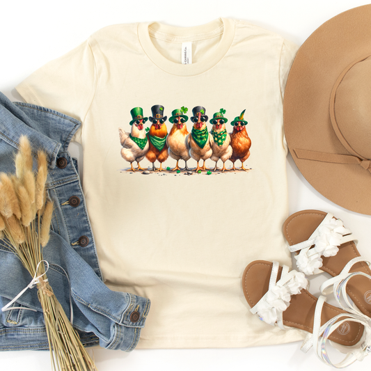 Cream-colored graphic tee featuring a quirky lineup of chickens dressed in St. Patrick’s Day attire with green bandanas, hats, and shamrocks. A fun and festive shirt for celebrating Irish luck and charm.