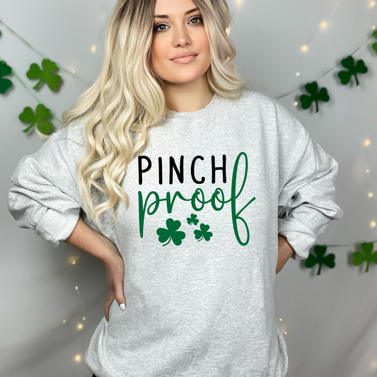 Light gray sweatshirt featuring the phrase 'Pinch Proof' in bold black and green letters, accented with cheerful shamrock illustrations. Perfect for celebrating St. Patrick’s Day in style while staying comfy and festive.